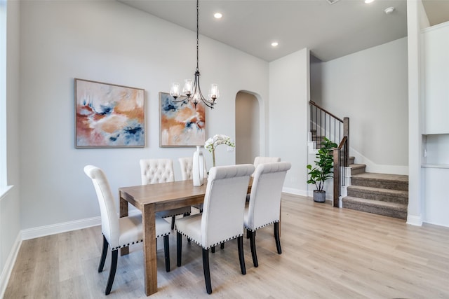 dining space featuring light wood-type flooring and a notable chandelier