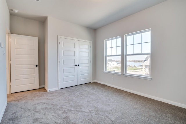 unfurnished bedroom with light colored carpet and a closet