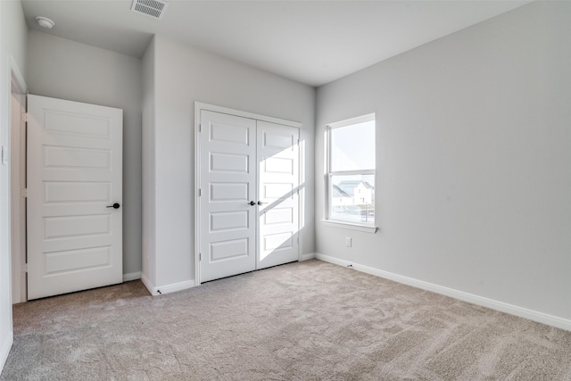 unfurnished bedroom with a closet and light colored carpet