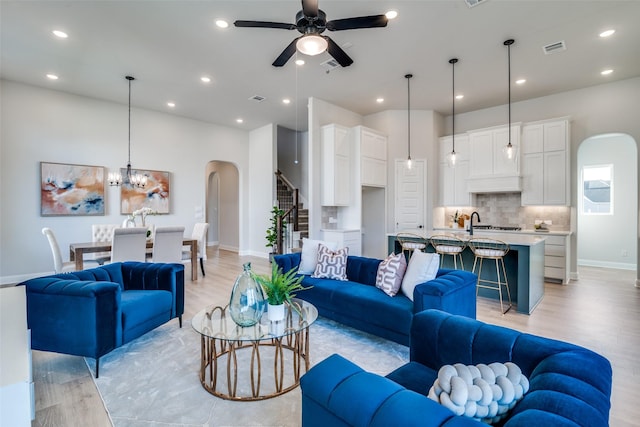 living room featuring ceiling fan with notable chandelier and light hardwood / wood-style flooring