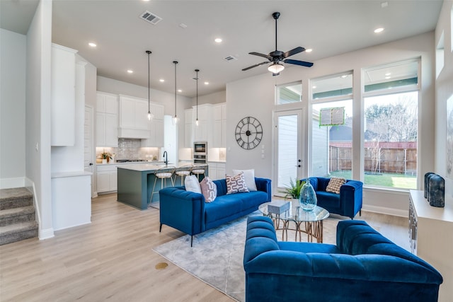 living room featuring ceiling fan, light hardwood / wood-style flooring, and sink