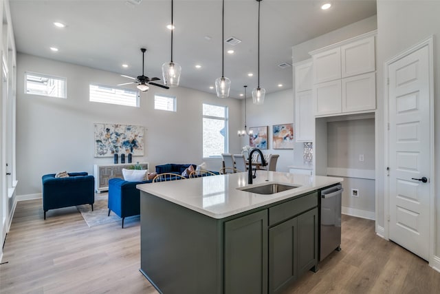 kitchen featuring ceiling fan, sink, stainless steel dishwasher, a center island with sink, and white cabinets