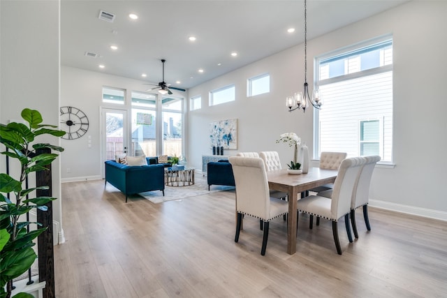 dining space with ceiling fan with notable chandelier and light hardwood / wood-style flooring