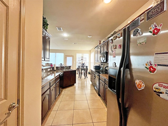 kitchen featuring sink, dark brown cabinets, light tile patterned floors, and stainless steel appliances