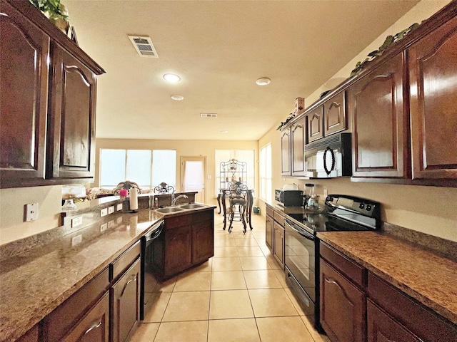 kitchen with black appliances, dark brown cabinets, light tile patterned floors, and sink