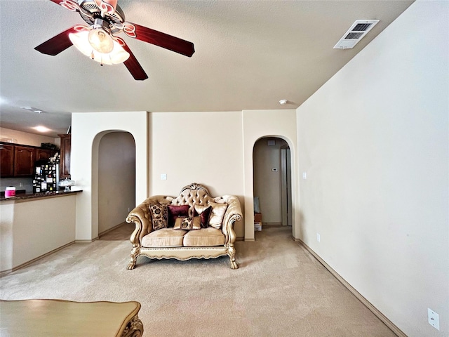 living area with ceiling fan and light colored carpet