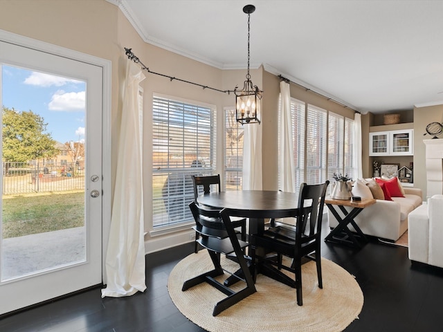 dining room with ornamental molding, dark hardwood / wood-style flooring, a healthy amount of sunlight, and a notable chandelier