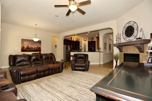 living room with ceiling fan and a tiled fireplace