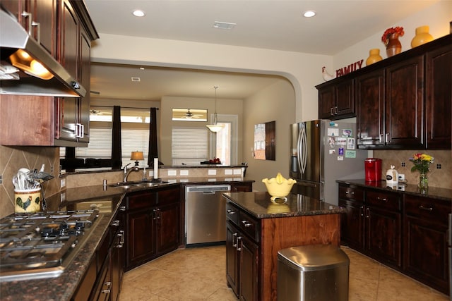 kitchen with sink, stainless steel appliances, tasteful backsplash, dark brown cabinets, and a kitchen island