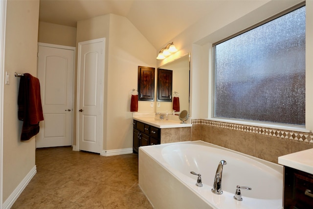 bathroom with vanity, a bathtub, plenty of natural light, and lofted ceiling