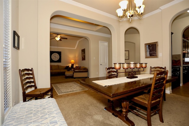 carpeted dining area with ceiling fan with notable chandelier and crown molding