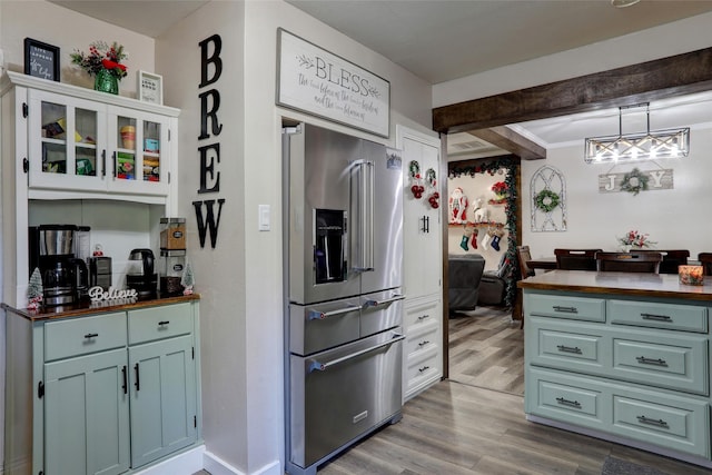 kitchen with pendant lighting, white cabinets, hardwood / wood-style flooring, high quality fridge, and butcher block countertops