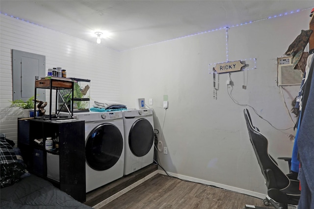 clothes washing area with a wall mounted air conditioner, dark hardwood / wood-style flooring, electric panel, and washer and clothes dryer