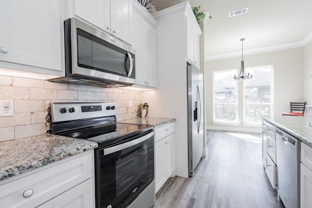 kitchen featuring backsplash, an inviting chandelier, ornamental molding, appliances with stainless steel finishes, and white cabinetry