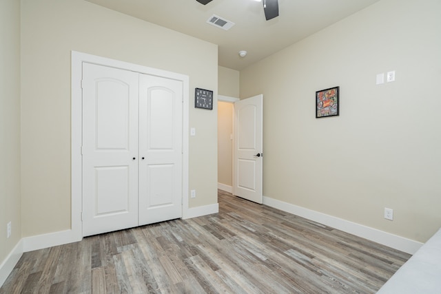 unfurnished bedroom with ceiling fan, a closet, and light wood-type flooring