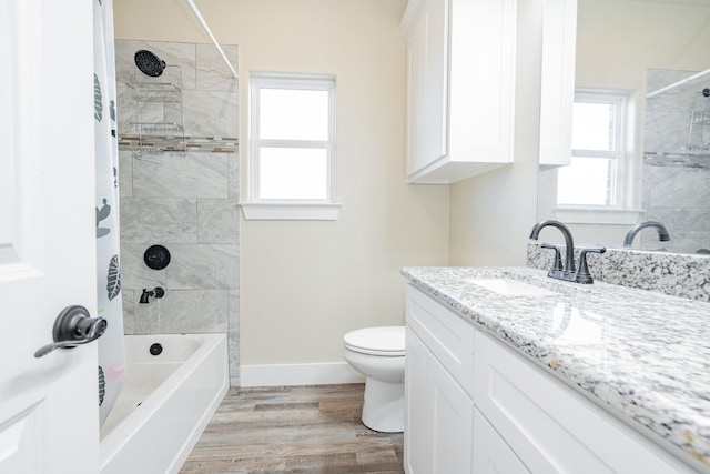 full bathroom featuring hardwood / wood-style floors, vanity, toilet, and tiled shower / bath