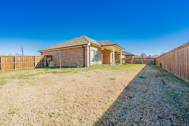 back of property featuring a yard and ceiling fan