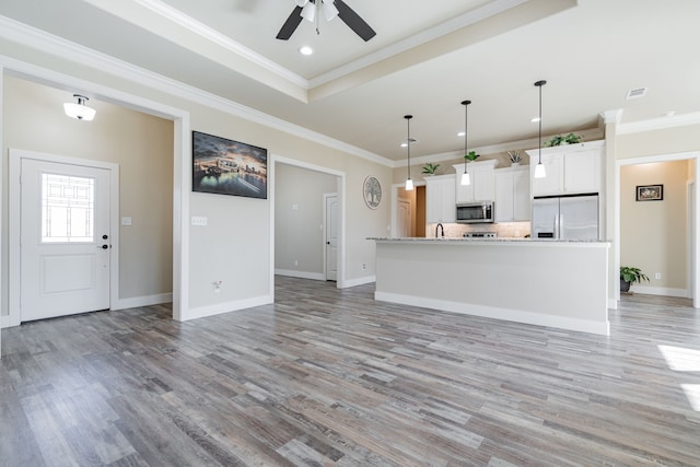 kitchen featuring stainless steel appliances, ceiling fan, a kitchen island with sink, white cabinets, and hanging light fixtures