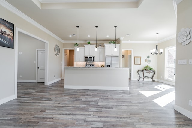 kitchen featuring decorative backsplash, appliances with stainless steel finishes, decorative light fixtures, white cabinetry, and an island with sink