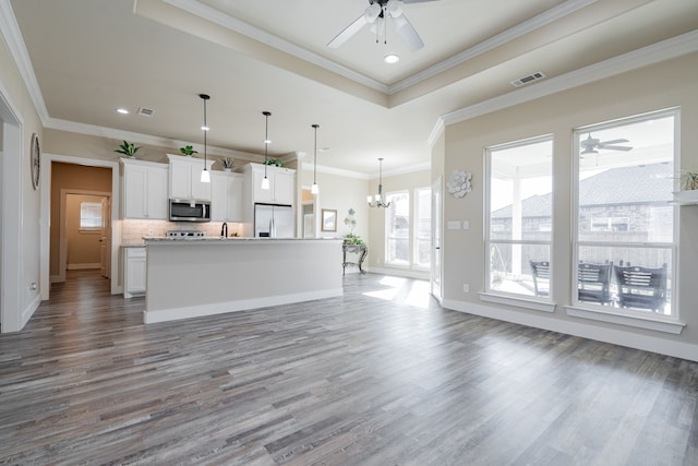 kitchen with stainless steel appliances, backsplash, decorative light fixtures, a kitchen island with sink, and white cabinets