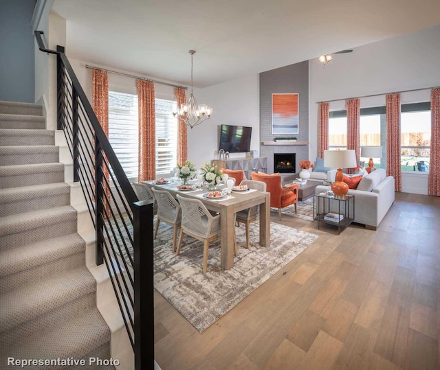 dining room with a healthy amount of sunlight, an inviting chandelier, a fireplace, and light wood-type flooring