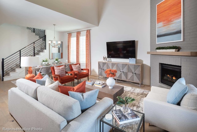 living room with an inviting chandelier, a fireplace, and light hardwood / wood-style flooring