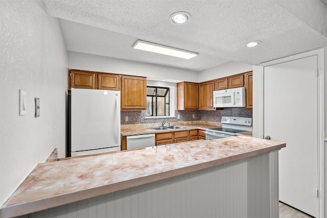 kitchen featuring a textured ceiling, decorative backsplash, white appliances, and sink