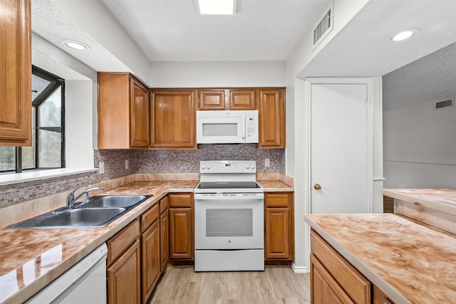 kitchen with wood counters, white appliances, sink, light wood-type flooring, and a textured ceiling