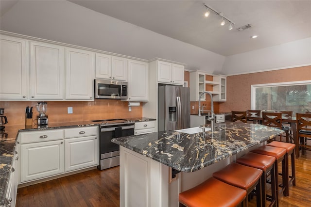 kitchen featuring white cabinetry, stainless steel appliances, and an island with sink