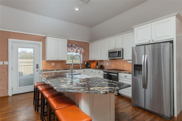 kitchen with dark stone counters, white cabinetry, a center island, and stainless steel appliances