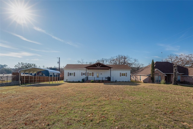 back of property with a carport and a yard