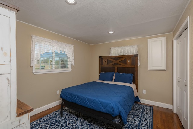 bedroom featuring a closet, dark wood-type flooring, and a textured ceiling