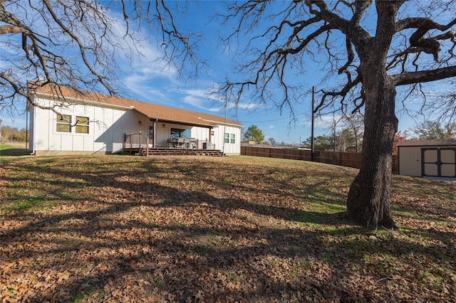 back of property with a yard, a storage unit, and a deck