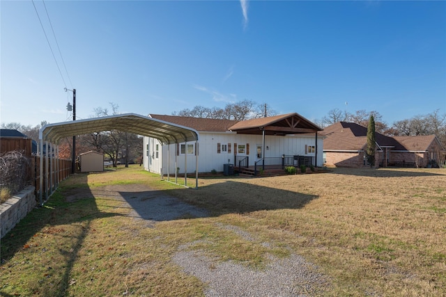 rear view of property with a lawn, central AC unit, and a carport