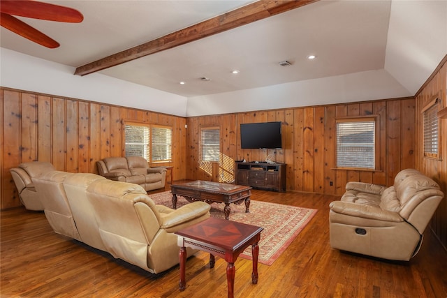 living room with ceiling fan, hardwood / wood-style floors, vaulted ceiling, and wooden walls