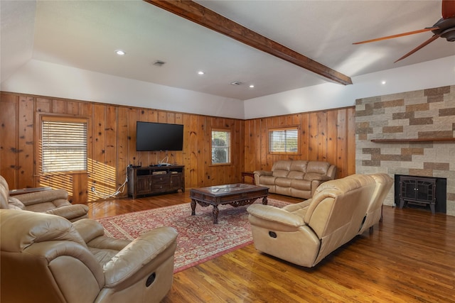 living room featuring hardwood / wood-style flooring, ceiling fan, wooden walls, and vaulted ceiling with beams