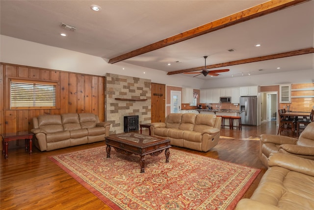 living room with beam ceiling, ceiling fan, wooden walls, and wood-type flooring