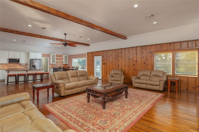 living room featuring hardwood / wood-style floors, ceiling fan, and beam ceiling