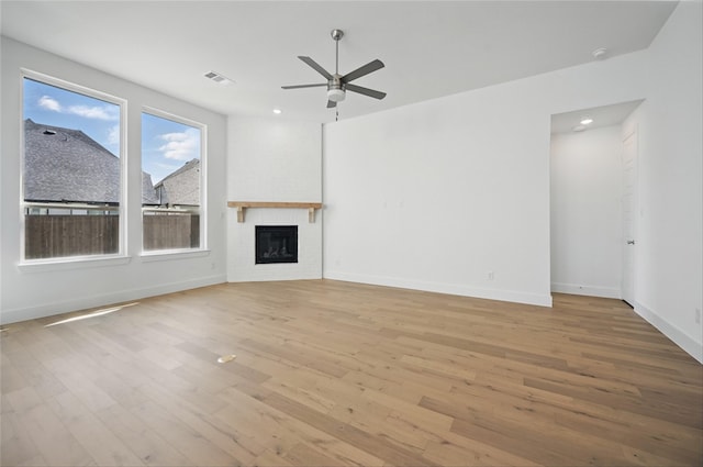 unfurnished living room featuring visible vents, ceiling fan, wood finished floors, and a large fireplace