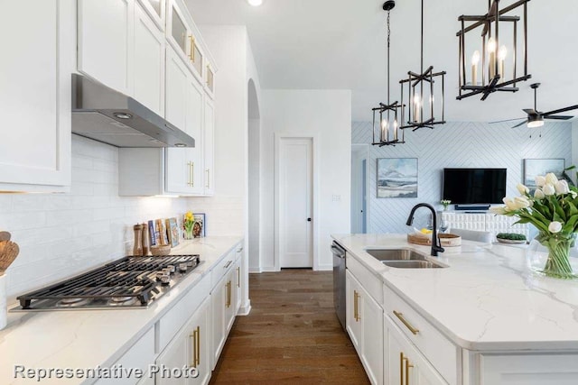 kitchen featuring appliances with stainless steel finishes, sink, exhaust hood, decorative light fixtures, and an island with sink