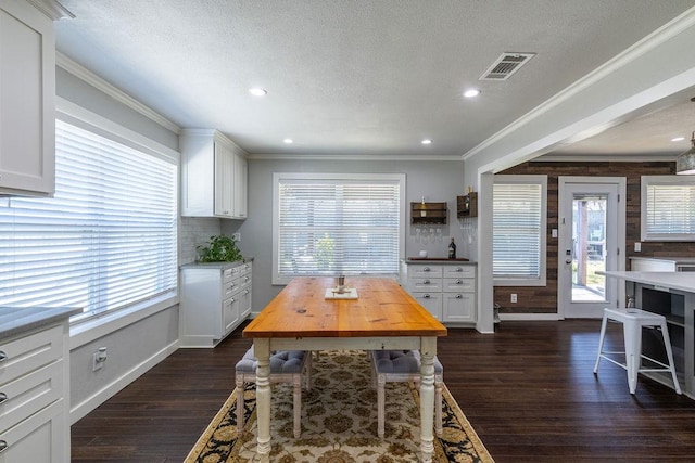 dining area with a textured ceiling, plenty of natural light, crown molding, and dark wood-type flooring