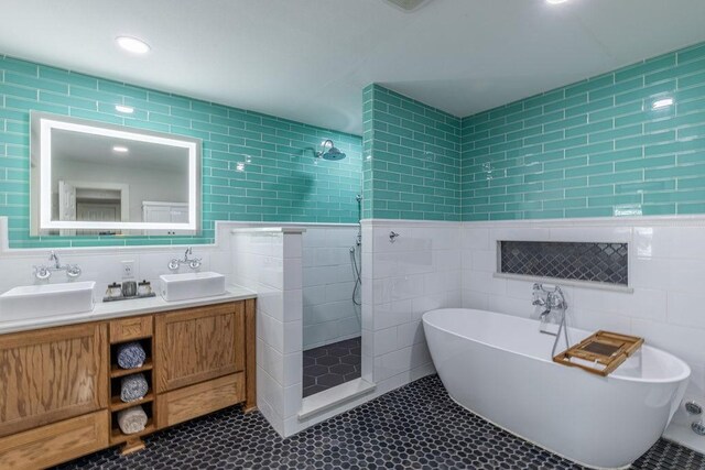 bathroom featuring plus walk in shower, vanity, and tile walls