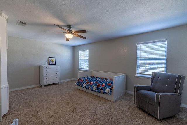 carpeted bedroom featuring ceiling fan, a textured ceiling, and multiple windows