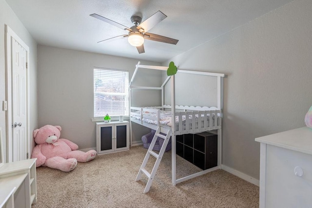 carpeted bedroom with a nursery area and ceiling fan