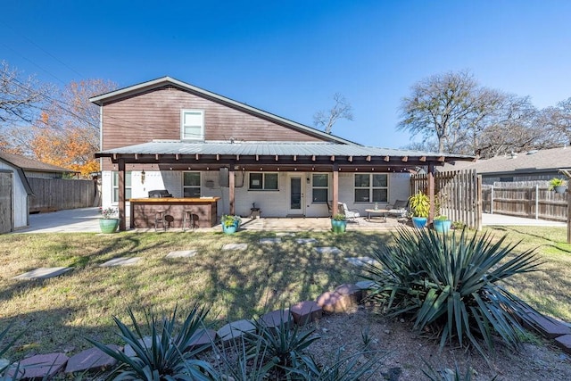 back of house featuring a yard, an outdoor kitchen, an outdoor bar, and a patio area