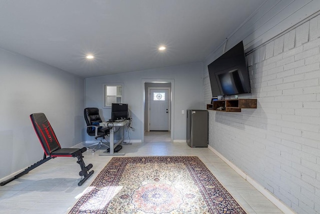 office featuring vaulted ceiling and brick wall