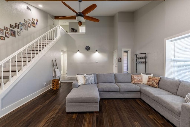 living room with a high ceiling, dark hardwood / wood-style flooring, and ceiling fan