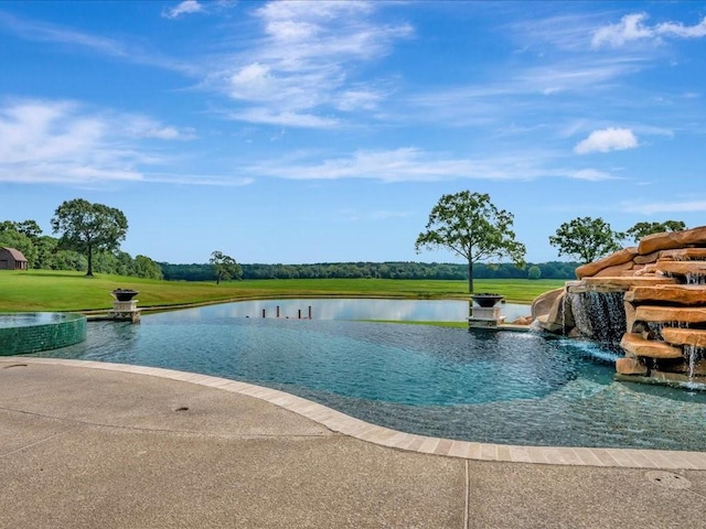 view of swimming pool featuring a yard, a water view, and an infinity pool