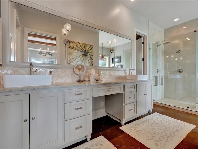 bathroom featuring decorative backsplash, a shower stall, double vanity, and a sink