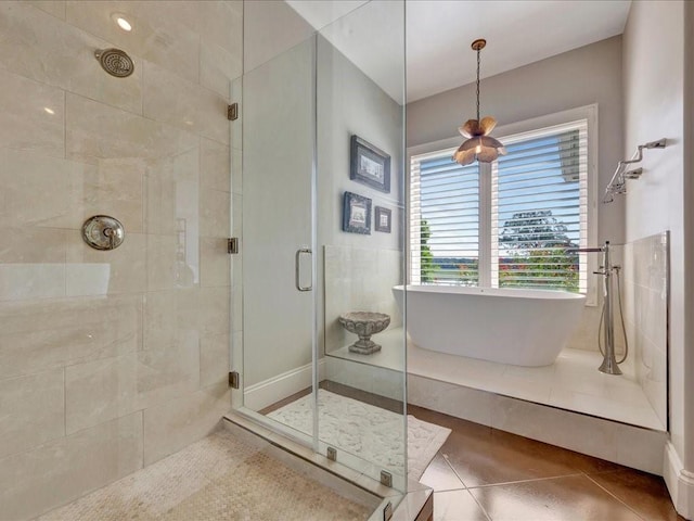 full bath featuring tile patterned flooring, a soaking tub, and a shower stall